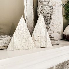 two white wooden ornaments sitting on top of a mantle next to a potted plant