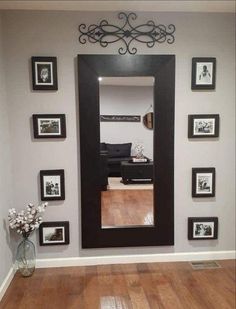 a large black framed mirror sitting on top of a wall next to a wooden floor