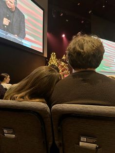 two people sitting in chairs watching television