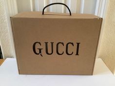 a gucci box sitting on top of a white table next to a wall and window