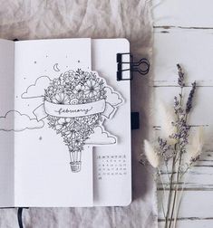 an open notebook sitting on top of a wooden table next to dried flowers and plants