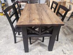 a wooden table with four chairs around it in a room filled with other furniture and tools