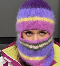 a woman wearing a purple and yellow striped knitted hat with a scarf around her face