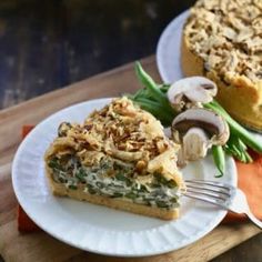 a slice of quiche on a plate next to a pie with mushrooms and asparagus