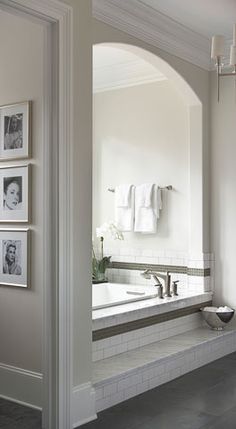 a bathroom with pictures on the wall and a bathtub in front of it's mirror