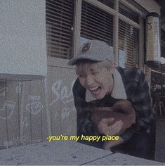 an old man wearing a hat and looking at his cell phone while standing in front of a building