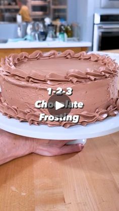 a person holding a chocolate frosted cake