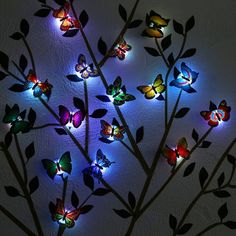 a tree with colorful lights on it in the shape of butterflies and leaves, against a white background