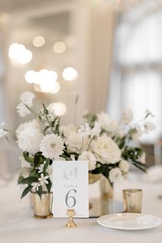 the table is set with white flowers and gold candlesticks for an elegant centerpiece