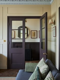 a living room with couches, mirrors and pictures on the wall above it's doors