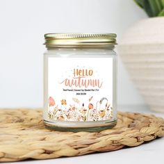 a jar filled with white candles sitting on top of a wicker mat next to a potted plant