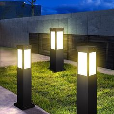 three lights that are in the grass near each other on some kind of pedestals