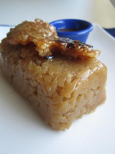 a piece of food sitting on top of a white plate next to a blue bowl