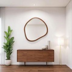 a large round mirror on the wall above a wooden cabinet in a white living room