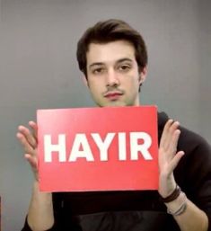 a man holding up a sign with the word hayir in front of his face