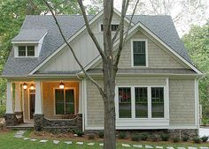 a gray house with white trim and green shutters on the front door is surrounded by trees