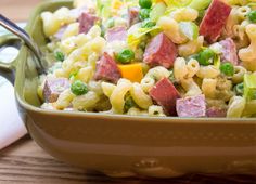 a bowl full of pasta salad with peas and ham