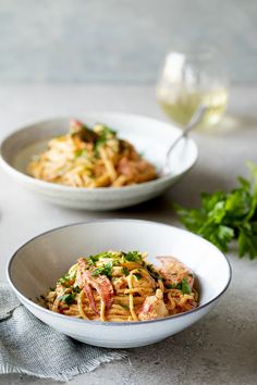 two bowls of pasta with shrimp and parsley