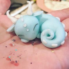 a small blue toy animal laying on top of someone's hand