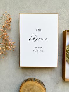 an open box with a sign on it next to a tree stump and some flowers