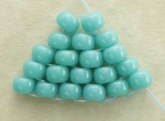 small blue beads are arranged in a triangle shape on a white tablecloth with a string