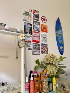 a surfboard is hanging on the wall next to some flowers and other things in front of it