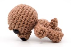 a crocheted teddy bear laying on its side with it's head down