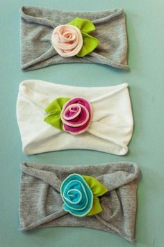 three headbands with flowers on them sitting next to each other in front of a blue wall