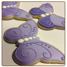 decorated cookies in the shape of butterfly wings on a white table with purple icing