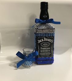 a bottle of jack daniels whiskey next to a shot glass with a blue bow on it