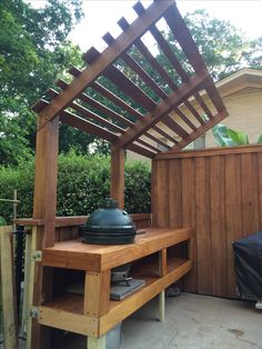 an outdoor grill built into the side of a wooden fence with a potted plant on top