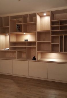 an empty living room with wood flooring and built in shelving units on the wall