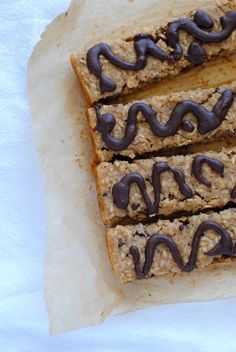 three bars with chocolate drizzled on them sitting on top of parchment paper