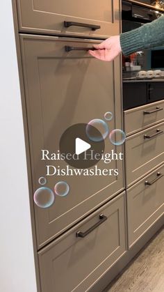 a woman is reaching for soap bubbles on the kitchen cabinet doors and drawer drawers that are in front of her