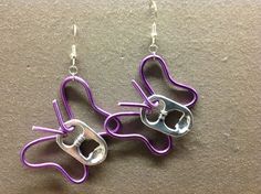 two pairs of purple and silver earrings on a gray surface with metal hooks attached to them