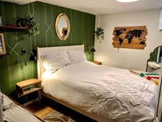 a bedroom with green walls, white bedding and a mirror on the wall above it