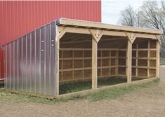 a metal shed with hay in it next to a red building