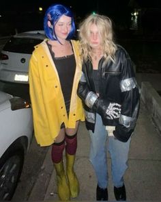 two women standing next to each other in front of a car