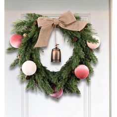 a christmas wreath hanging on the front door with ornaments around it and a bell in the middle