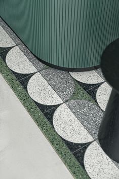 a black and white tiled floor next to a green metal structure with circles on it