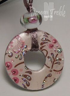 a pink and white donut with flowers on it's side hanging from a cord