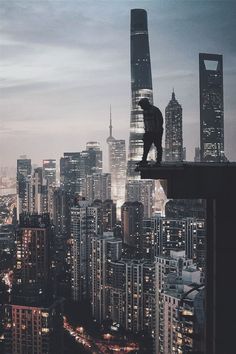 a man standing on top of a tall building in the middle of a city at night