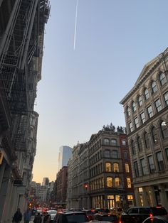 an airplane is flying in the sky over some buildings and cars on a city street