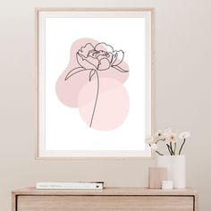 a white vase with flowers sitting on top of a dresser next to a framed print