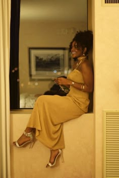 a woman in a yellow dress sitting on a window sill