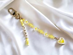 a yellow and white beaded keychain on a white satin