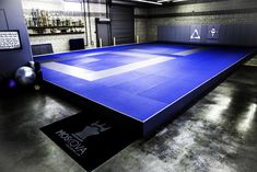 an indoor gym with blue mats and black flooring