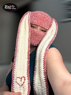 a woman wearing a scarf with a heart drawn on it's side and covering her face