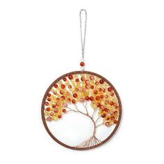 a glass ornament with a tree and orange beads hanging from it's side