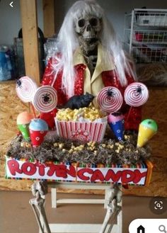 a table topped with lots of candy and candies next to a skeleton holding a cupcake